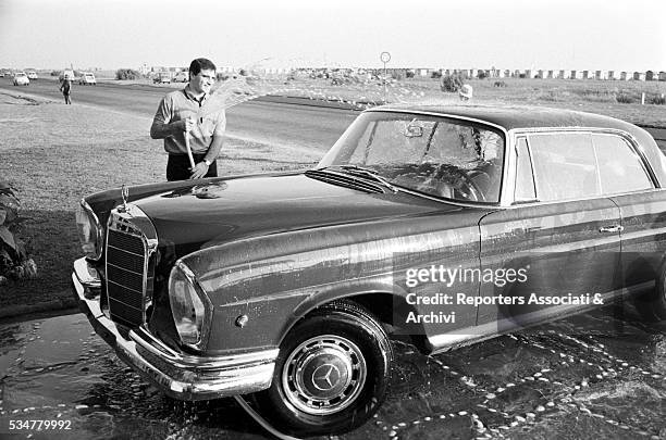 Italian singer Edoardo Vianello posing while washing his Mercedes. Italy, 20th August 1964