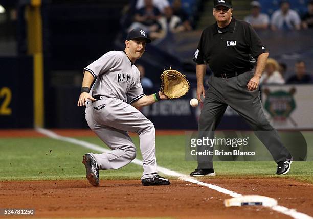 First baseman Dustin Ackley of the New York Yankees fields the ground out by Hank Conger of the Tampa Bay Rays to end the third inning of a game on...
