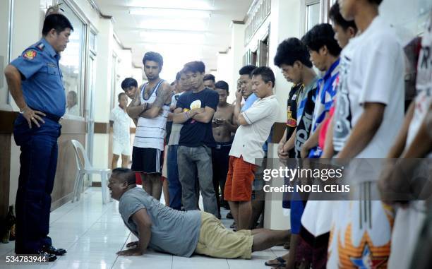 Men who violated the 10pm liquor ban, seen drinking on public places, are temporarily detained and made to do 40 push-ups at a police headquarters in...