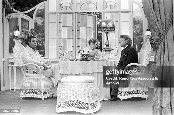 Italian actors Marcello Mastroianni, Lino Toffolo and Claudia Mori sitting at the table on the set of the film Lunatics and Lovers. 1976