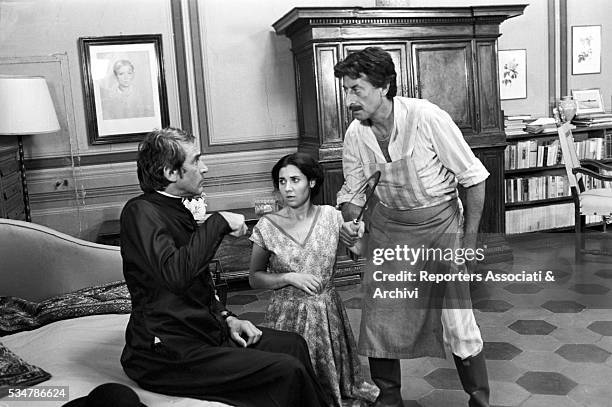 Italian actor Walter Chiari - dressed as priest - being threatened by a man wielding a sickle in front of Italian showgirl Marisa Laurito in the film...