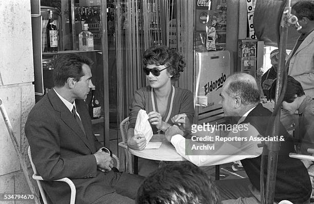 Italian director Luigi Comencini and Italian actorsi Walter Chiari and Anna Maria Ferrero sitting at the table in a café on the set of the film...