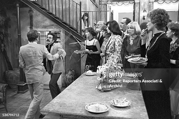 Italian actresses Milena Vukotic and Carla Gravina standing before two men fighting in the film The Terrace. 1980
