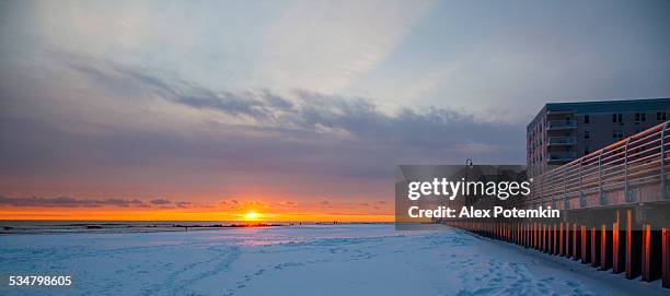 tracks on snowy ground at sunset on long beach next to wall. - nassau county bildbanksfoton och bilder