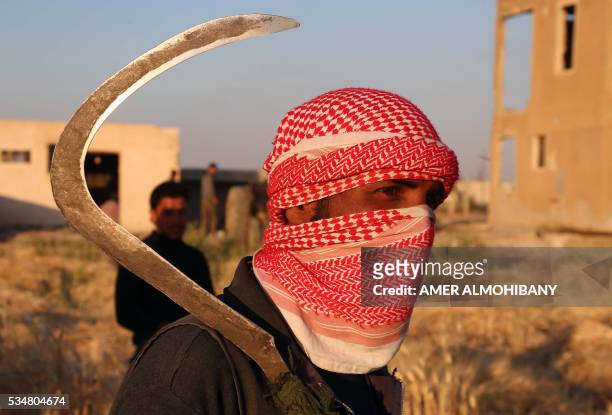 Syrian man holds a sickle after harvesting wheat in a field near the rebel-held village of al-Bahariyah, in the eastern Ghouta region on the...