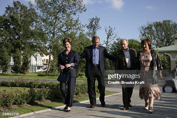 President George W. Bush and first lady Laura Bush walk to a social dinner with Russian President Vladimir Putin and his wife Lyudmila on the grounds...