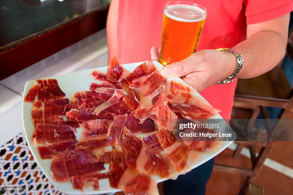 Hand holds tray of thinly sliced Jamon Iberico ham