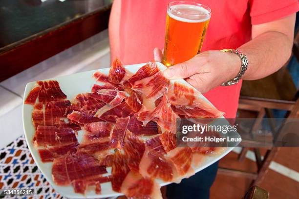 hand holds tray of thinly sliced jamon iberico ham - seville food stock pictures, royalty-free photos & images