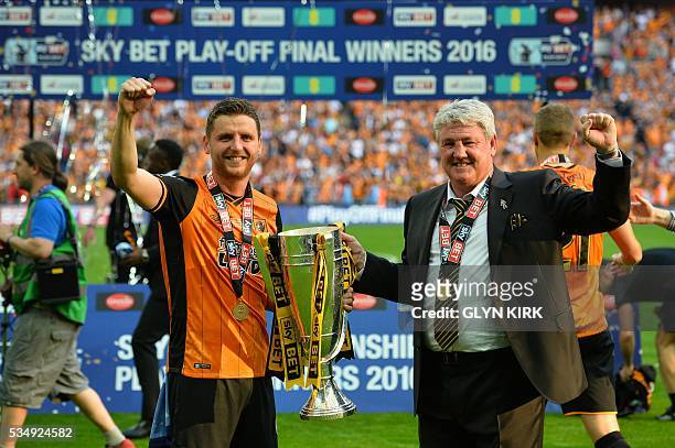 Hull City's Northern Irish defender Alex Bruce and Hull City's English manager Steve Bruce celebrate with the trophy after Hull City won the English...