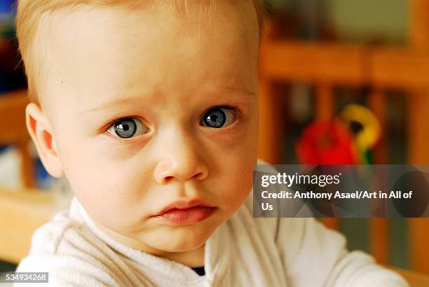 Ukraine, Kiev, Portrait of a white blond baby boy with big blue eyes wide open, and a sad surprised look on his face