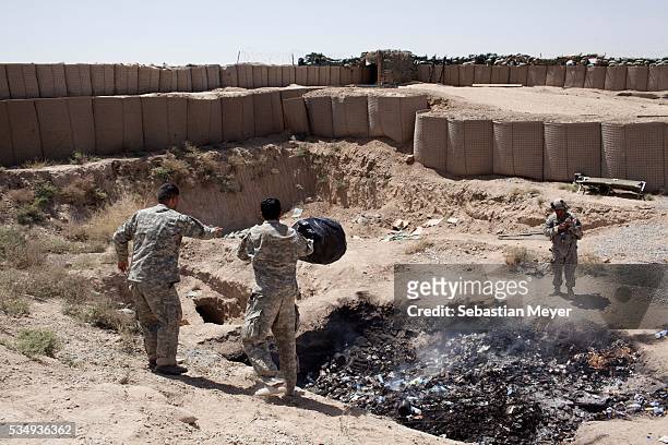Two interpreters for Bravo troop dump their trash in the base's "burn pit." Bravo "Bonecrusher" Troop of the 1-75 Cavalry, 101st Airborne Division...