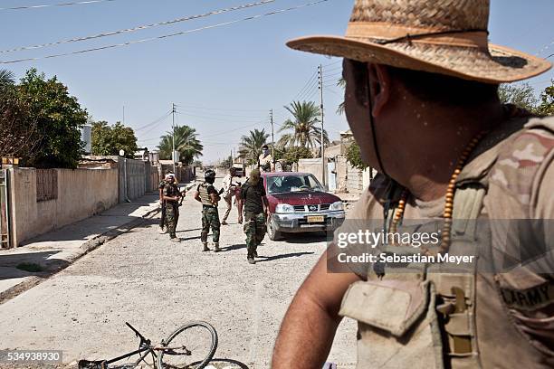 September 5: A Kurdish peshmerga soldier watches militiamen from the Badr Brigade move around the town of Suleiman Beg. After the loose coalition...