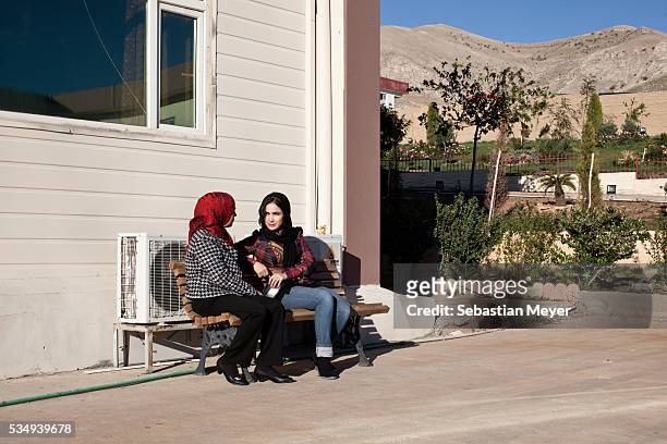 Two students sit and talk on a bench on the new campus of Sulaimaniyah University.