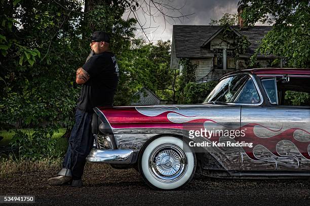 man leaning against front of 1957 ford custom car painted in red and silver flame design - voiture de collection photos et images de collection