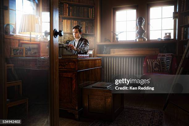 young man sitting at old-fashioned desk using vintage typewriter in 1920s-era library - bureau 1920 photos et images de collection