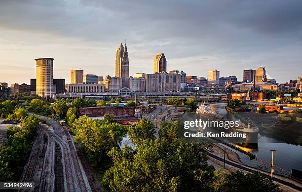 dusk skyline of downtown cleveland ohio with freighter on the cuyahoga river - downtown cleveland ohio stock pictures, royalty-free photos & images