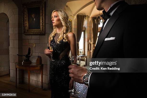 young formally dressed couple holding champagne glasses in grand hall - drinking champagne stock pictures, royalty-free photos & images