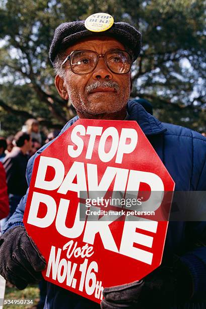 An African American man holds a sign reading, "Stop David Duke." Duke, a former Green Dragon in the Ku Klux Klan and proponent of "white rights," is...