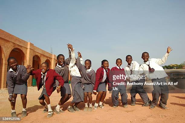 Nigeria, Jos, Schoolboys and schoolgirls, holding each others hand, and standing in line, smiling and waving