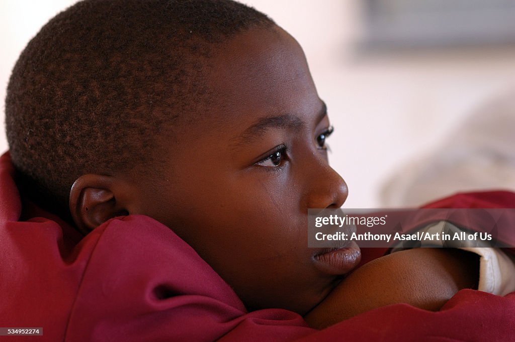 Nigeria, Jos, Portrait of a schoolboy wearing a purple vest, looking thoughtfully in front of him