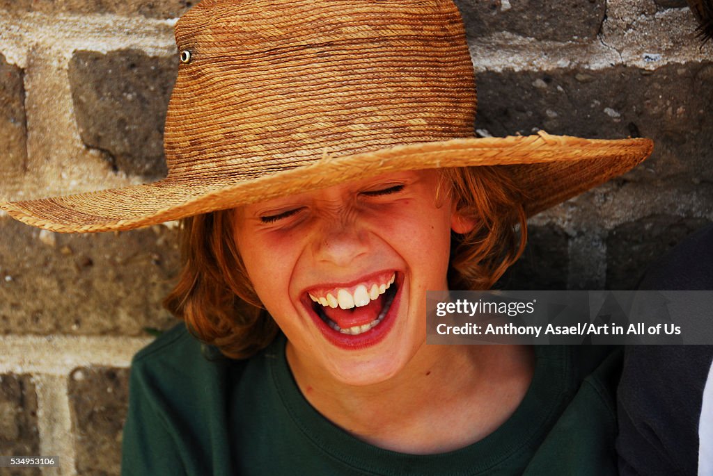 Mexico, San Miguel de Allende, close-up of a cheerful girl in straw hat, enjoying in front of a wall