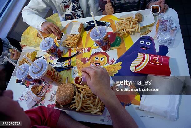 Children eating hamburgers, french fries, and chicken nuggets from McDonald's.