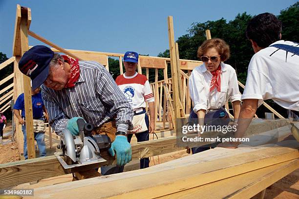 Jimmy Carter and wife Rosalynn Carter sawing lumber for a house for Habitat for Humanity. The Carters lead the Jimmy Carter Work Project for Habitat...