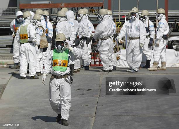 Workers wearing protective suits and masks are seen next to the No.4 reactor at Tokyo Electric Power Co. 's tsunami-crippled Fukushima Daiichi...