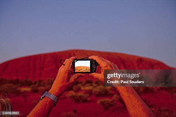 tourist photographing ayers rock in the australian outback - uluru rock stock-fotos und bilder