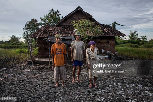 Suwadi , his wife, Saniaka , and their son Yono , stand behind their house which is affected by mudflow on May 27, 2016 in Sidoarjo, East Java,...