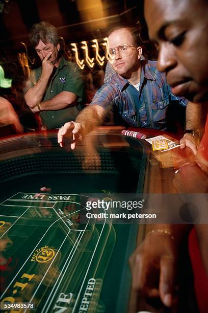Gambler tosses the dice on the craps table as others watch at Sam's Town Casino a day before it's grand opening.