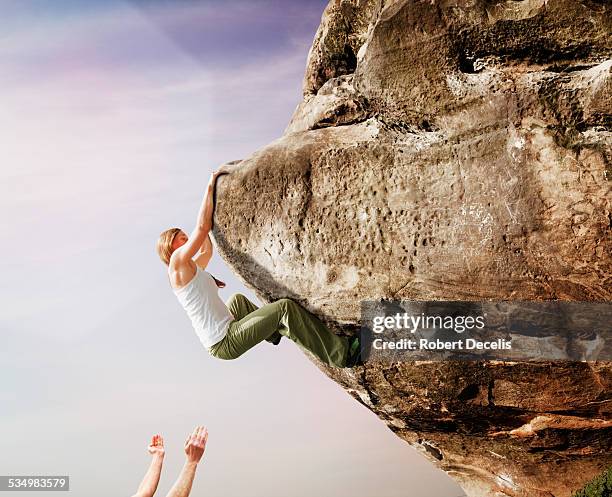 female free climber climbing rock face - escalada libre fotografías e imágenes de stock