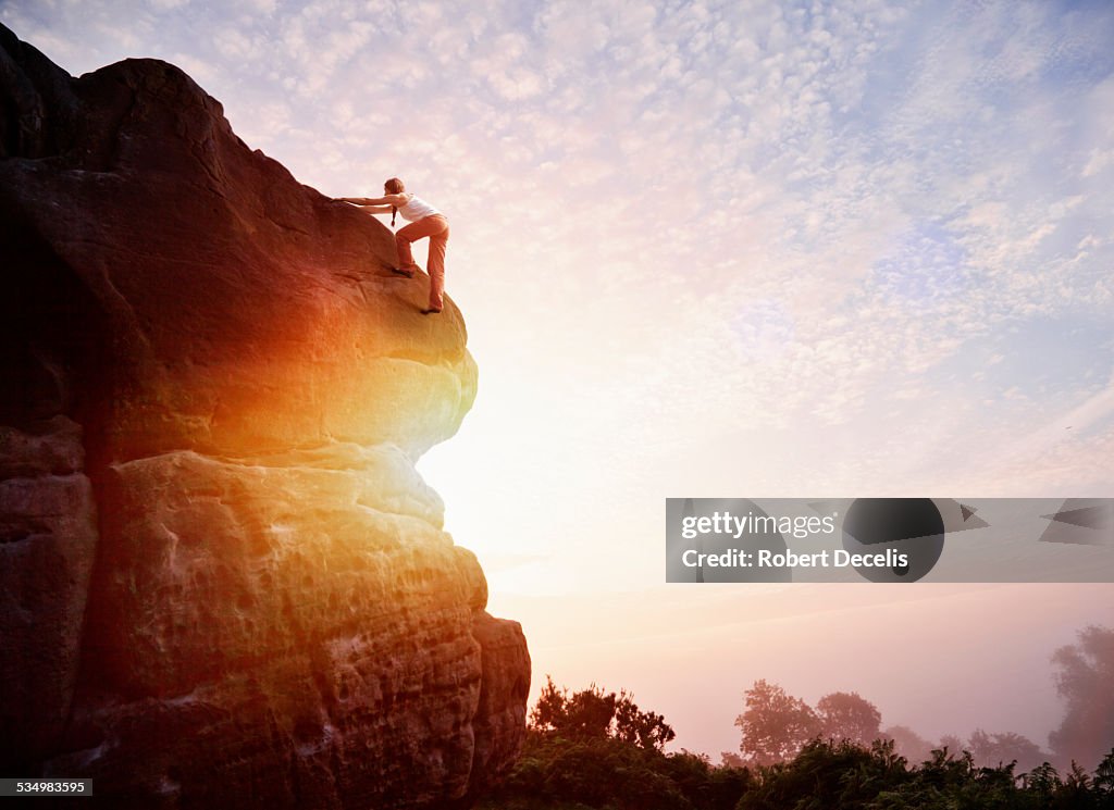 Female solo climber nearing summit of rock