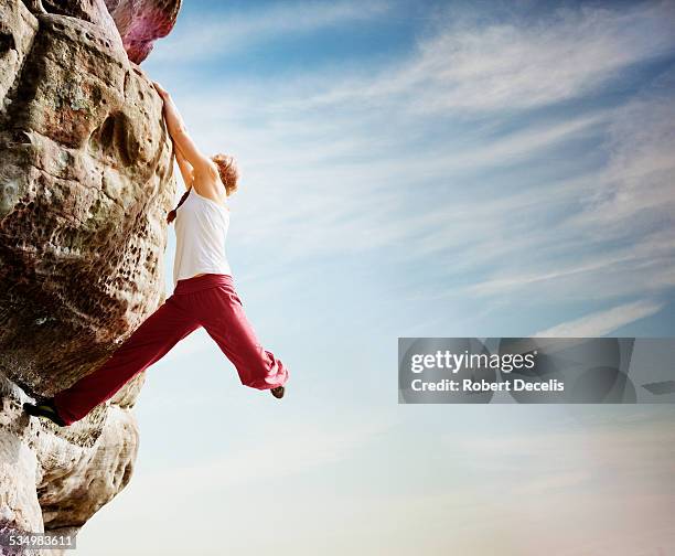 female free climber hanging from boulder - escalada libre fotografías e imágenes de stock