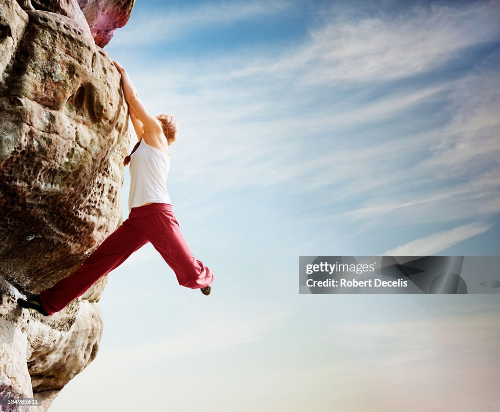 Female free climber hanging from boulder
