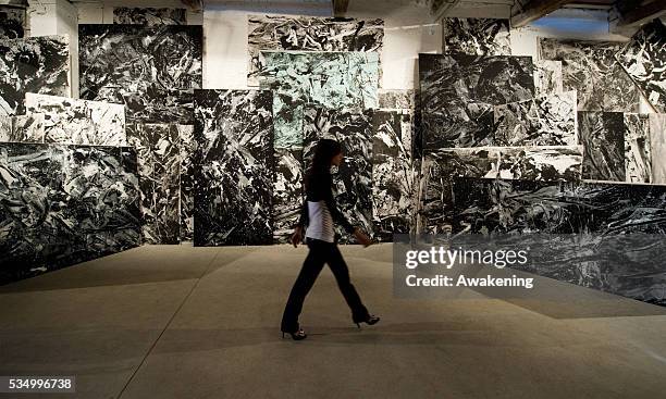 Woman walks in front of of the installation 'Emilio Vedova .....in continuum' composed of 115 canvases, most of which in black and white, produced in...