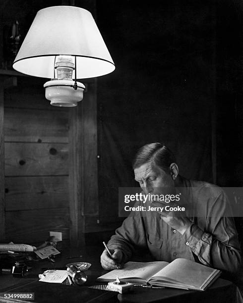 Poet W.H. Auden writing poetry in a bookkeeping ledger at his home on Fire Island, New York.