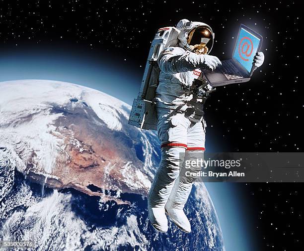 astronaut holding a laptop - at symbol fotografías e imágenes de stock