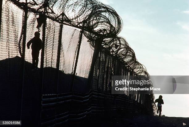 children playing near barbed wire border fence - emigration and immigration stock pictures, royalty-free photos & images