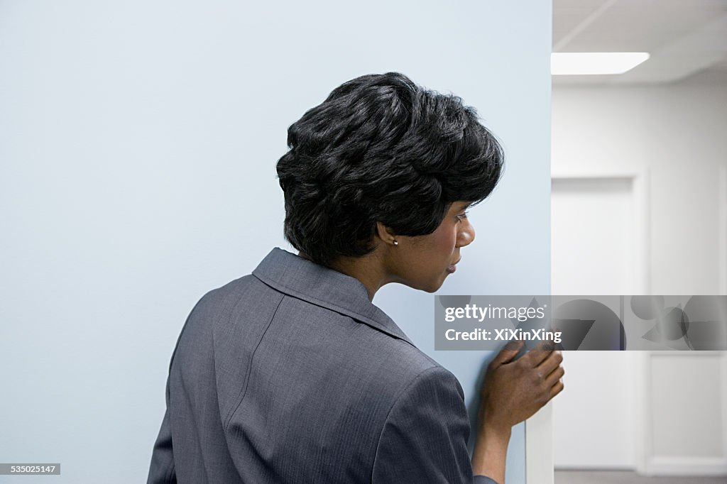 Woman hiding peering round corner