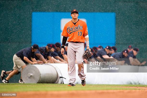 Manny Machado of the Baltimore Orioles walks off the field as the Cleveland Indians grounds crew rolls out the tarp during a rain delay in the eighth...