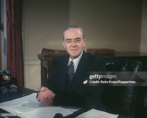 British Labour Party politician and Chancellor of the Exchequer, Sir Stafford Cripps pictured sitting at his desk in the Treasury in London in...
