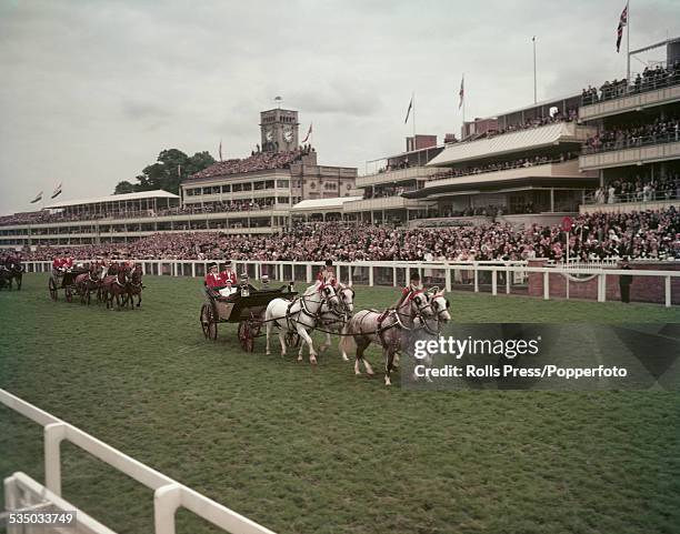 Queen Elizabeth II and Prince Philip, Duke of Edinburgh ride in an open carriage during the Royal procession before the start of racing at Royal...