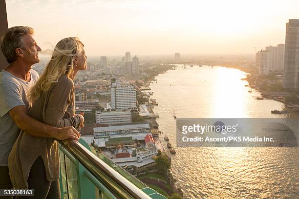 couple look out across city skyline from hi-rise - balcony view stockfoto's en -beelden