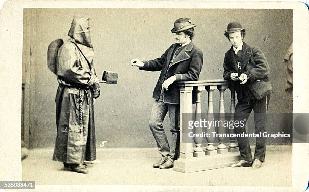 Hooded representative of a Catholic brotherhood asks for donations in his metal box, from Rome, Italy around 1860.