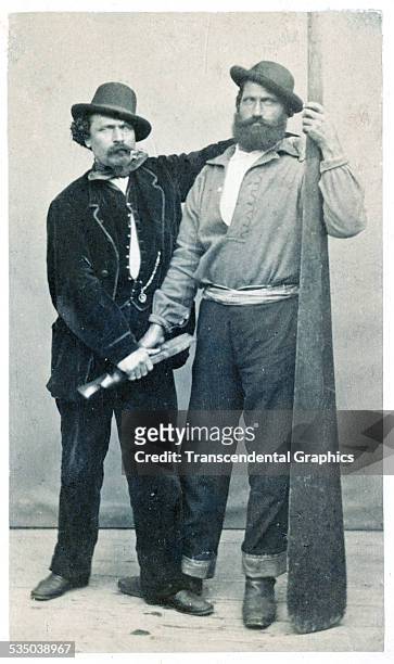 Pair of gondoliers pose in a photo studio with the tools of their trade in Venice, Italy around 1860.