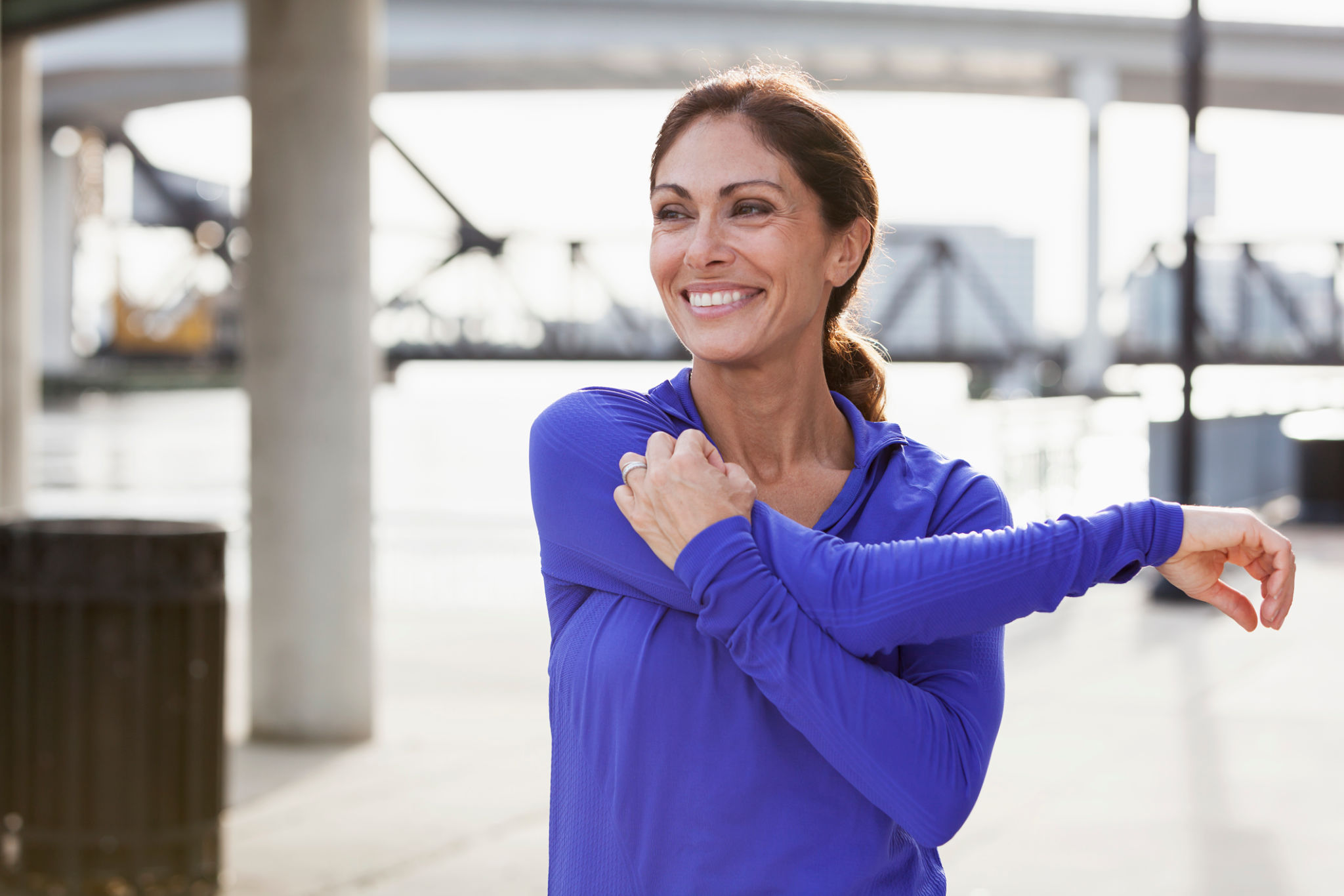Mature woman stretching during a jog on waterfront Mature woman stretching during a jog on waterfront