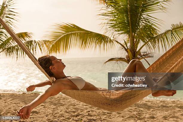 frau genießen sie ein bisschen regen und entspannen sie in einer hängematte am strand - caribbean sea stock-fotos und bilder