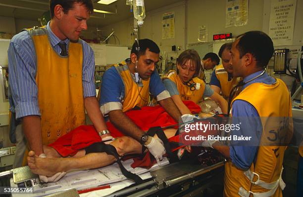 At the Royal London Hospital, accident and emergency medical staff wearing radiation-proof x-ray lead tunics very carefully move a patient to a more...