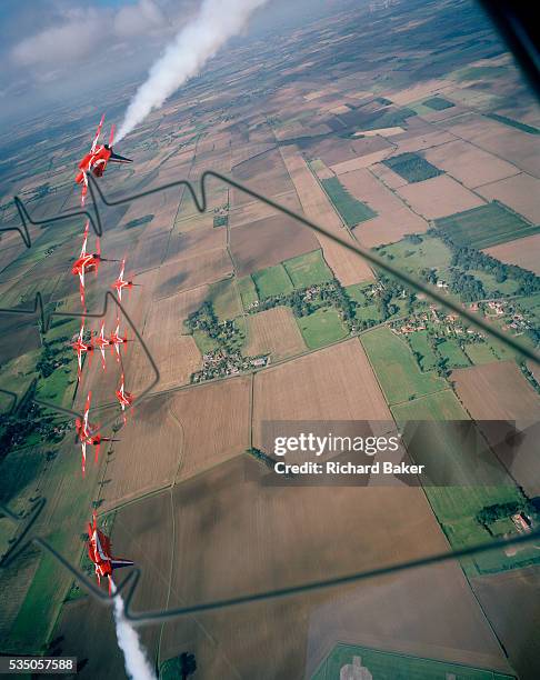 Banking hard right over the agricultural Lincolnshire countryside are the elite 'Red Arrows', Britain's prestigious Royal Air Force aerobatic team,...